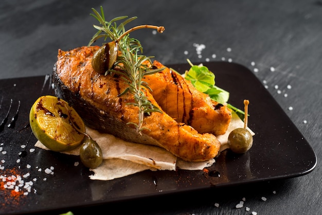 Gros steak de poisson grillé sur le fond en bois noir