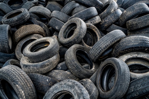 Gros tas de pneus automobiles sur l'usine en panne. De nombreux pneus en caoutchouc noir sur le sol à l'intérieur de l'ancien immense bâtiment vide.