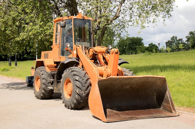 Gros tracteur orange avec godet prêt à partir