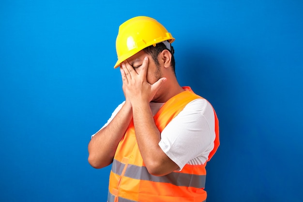 gros travailleur de la construction asiatique homme portant un uniforme et un casque couvrant les yeux avec les mains