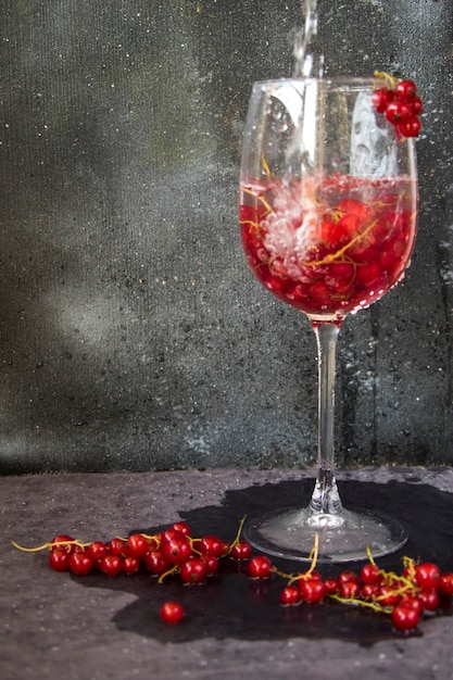 Groseille rouge dans le verre à vin sur fond gris et bleu. Grand groupe de baies colorées.