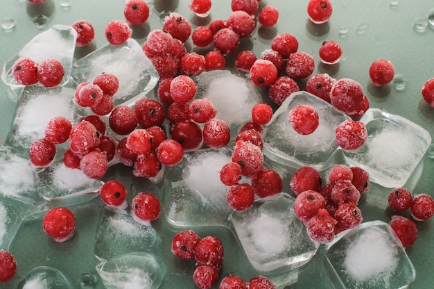 Groseille rouge mûre congelée sur des glaçons sur une surface verte