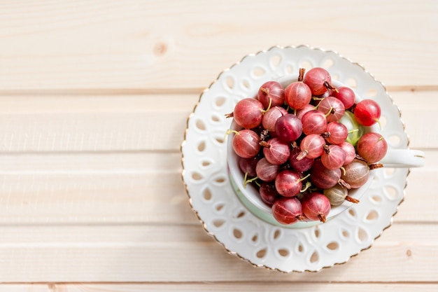 Groseilles rouges douces fraîches dans une tasse en céramique sur fond de boisBaies fraîches juteuses dans une tasse aliments d'été sains, ils sont bons pour les capacités cognitives de l'immunité visuelle