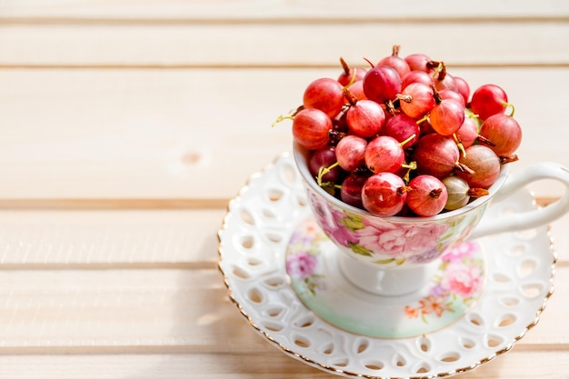 Groseilles rouges douces fraîches dans une tasse en céramique sur fond de boisBaies fraîches juteuses dans une tasse aliments d'été sains, ils sont bons pour les capacités cognitives de l'immunité visuelle