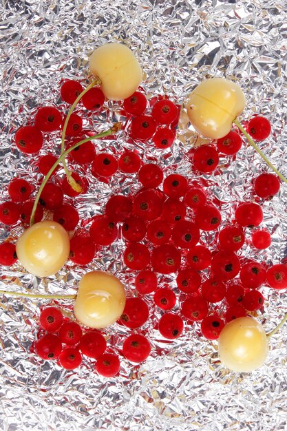 Photo groseilles rouges juteuses sucrées et cerises jaunes sur fond d'aluminium vue de dessus concept de cuisine végétarienne