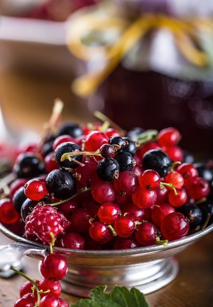 Groseilles rouges et noires dans un bol rustique sur la table de la cuisine.