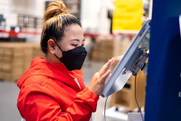 Photo grosse femme ouvrière inspectant le stock de produits tout en travaillant dans un grand entrepôt masque facial pendant l'épidémie de coronavirus et de grippe protection contre les virus et les maladies