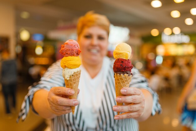 Grosse femme tenant des glaces au restaurant de restauration rapide