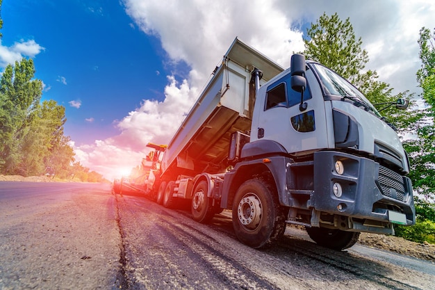 Une grosse technique professionnelle lourde pose des réparations de routes asphaltées en journée ensoleillée Gros plan