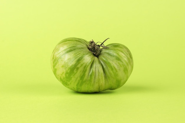 Une grosse tomate verte sur fond vert