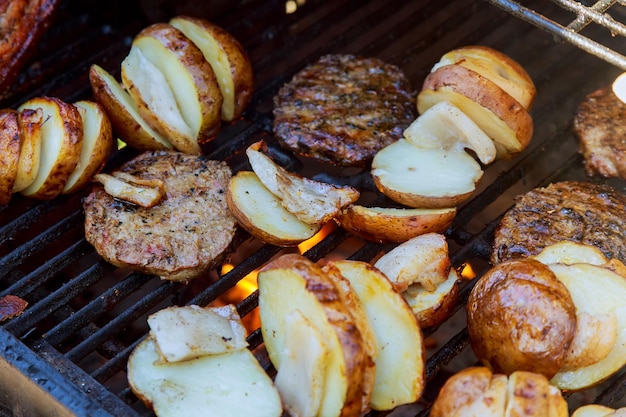 Grosse tranche de pommes de terre VillageStyle sur un barbecue chaud sur un gril à charbon Flammes de feu en arrière-plan