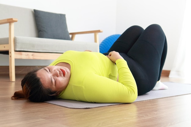 Les grosses femmes asiatiques font de l'exercice pour perdre du poids Elle était fatiguée et se reposait sur le parquet de la maison Concept sportif exercice sain