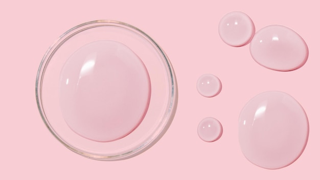 Grosses gouttes de gel d'eau liquide sérum cosmétique sur fond rose