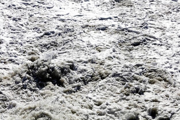 De grosses vagues se brisant sur le rivage avec du forma blanc