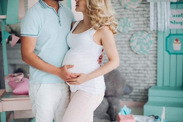 Grossesse jeune famille debout parmi les jouets