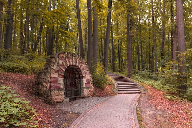 Grotte dans le parc d'une grille fermée. Chemin forestier