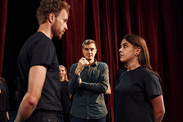 Groupe d'acteurs vêtus de vêtements de couleur foncée en répétition au théâtre