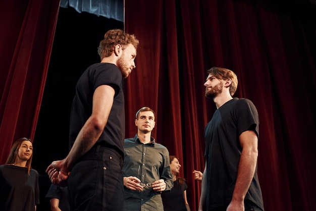 Groupe d'acteurs vêtus de vêtements de couleur foncée en répétition au théâtre