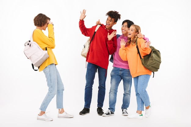 Groupe d'adolescents joyeux isolés, portant des sacs à dos, prenant une photo