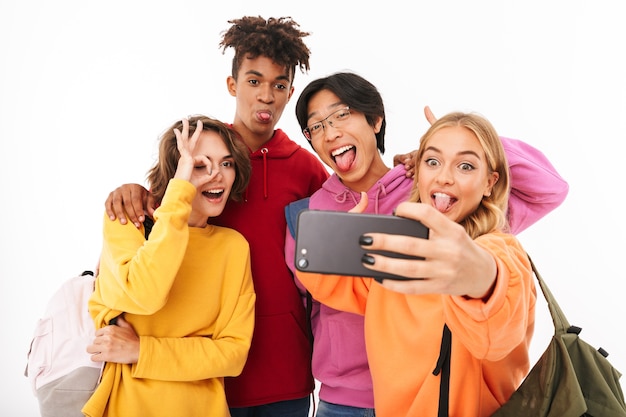 Groupe d'adolescents joyeux isolés, portant des sacs à dos, prenant un selfie