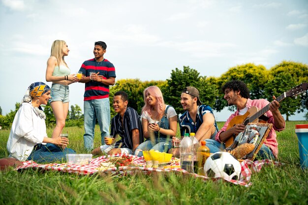 Un groupe d'adolescents multiethniques passe du temps à l'extérieur pour un pique-nique dans le parc.