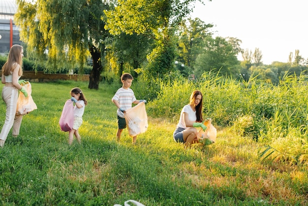 Un groupe d'adultes et d'enfants ensemble au coucher du soleil est engagé dans la collecte des ordures dans le parc Recyclage des déchets de protection de l'environnement Tri des ordures