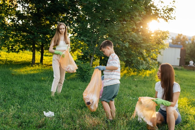 Un groupe d'adultes et d'enfants ensemble au coucher du soleil est engagé dans la collecte des ordures dans le parc Recyclage des déchets de protection de l'environnement Tri des ordures