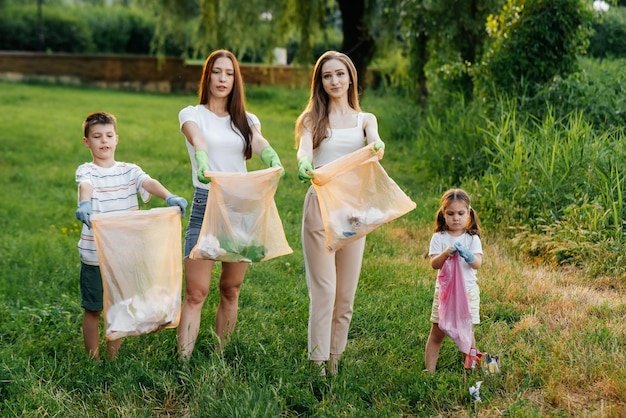 Un groupe d'adultes et d'enfants ensemble au coucher du soleil est engagé dans la collecte des ordures dans le parc Recyclage des déchets de protection de l'environnement Tri des ordures