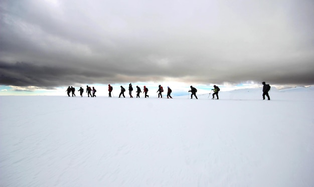 Groupe d'alpinistes marchant dans les montagnes couvertes de neigexAxA