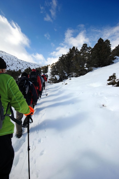 Groupe d'alpinistes marchant dans les montagnes couvertes de neigexAxA