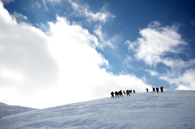 Groupe d'alpinistes marchant dans les montagnes couvertes de neigexAxA