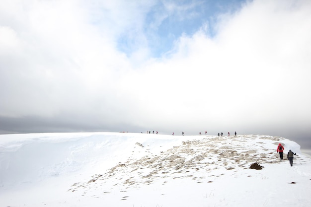 Groupe d'alpinistes marchant dans les montagnes couvertes de neigexAxA