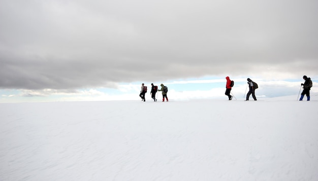 Groupe d'alpinistes marchant dans les montagnes couvertes de neigexAxA