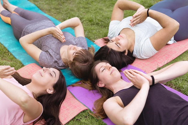 Groupe d'amies caucasiennes pratiquant le yoga à l'extérieur