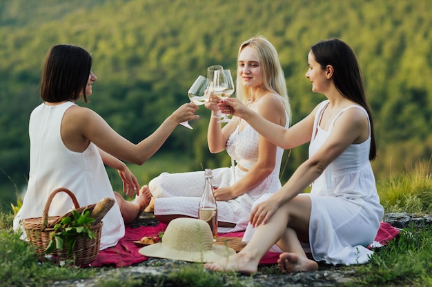 Groupe d'amies avec des verres à vin se détendre sur pique-nique