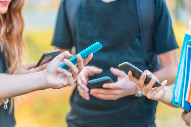 Groupe d'amis adolescents avec smartphones au parc