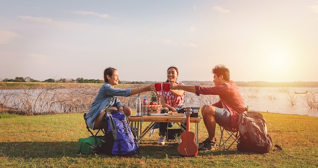 Un groupe d'amis asiatiques buvant du café et prenant le temps de faire un pique-nique pendant les vacances d'été. Ils sont heureux et s'amusent en vacances.