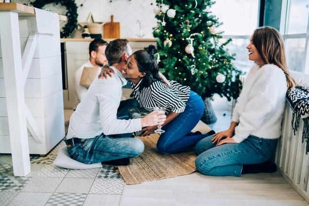 Groupe d'amis assis par terre à Noël