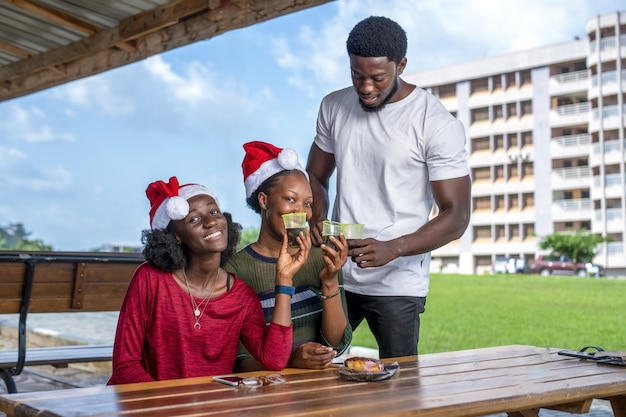 Groupe d'amis buvant une tasse de café avec dessert tout en célébrant Noël