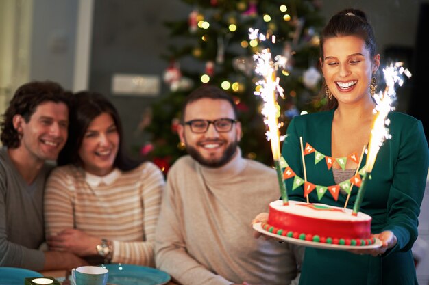 groupe d'amis célébrant Noël à la maison en savourant un gâteau de Noël