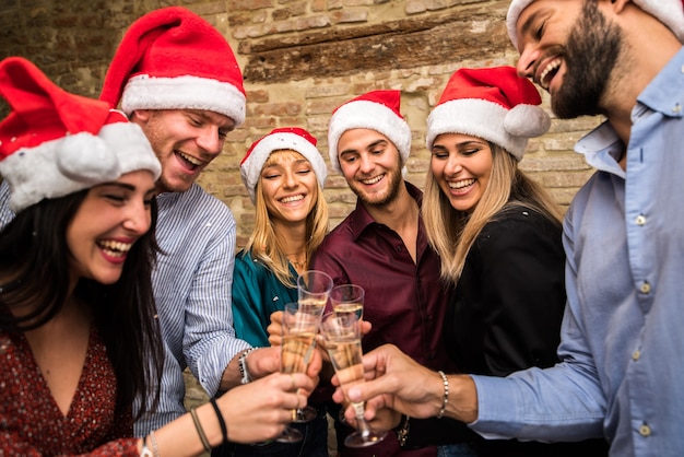 Groupe d'amis avec des chapeaux de père Noël pour célébrer Noël