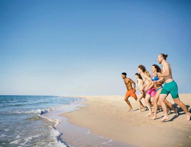 Groupe d'amis courir dans la mer bleue. Concept de l'heure d'été