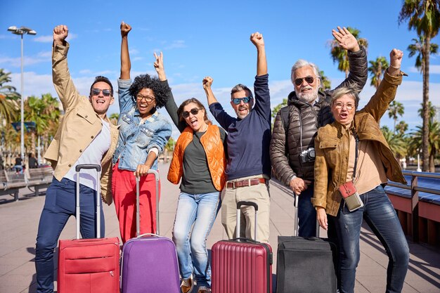 Un groupe d'amis excités d'âge moyen posant pour la caméra célébrant joyeusement leurs vacances