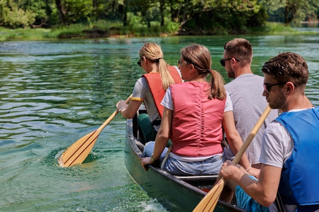 Groupe d'amis explorateurs aventureux font du canoë dans une rivière sauvage entourée par la belle nature