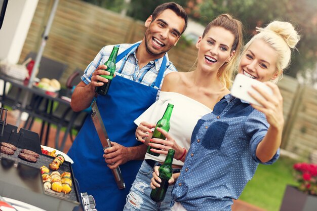 groupe d'amis faisant un barbecue et prenant un selfie