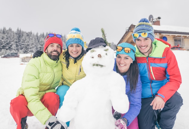 Groupe d'amis fait un bonhomme de neige