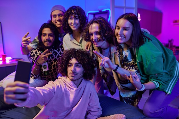 Groupe d'amis gais adolescents en vêtements décontractés prenant selfie