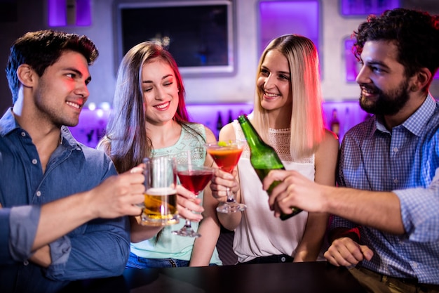 Groupe d'amis grillage cocktail, bouteille de bière et verre de bière au comptoir du bar