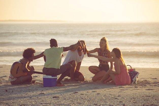 Un groupe d'amis grillant des bouteilles de bière sur la plage