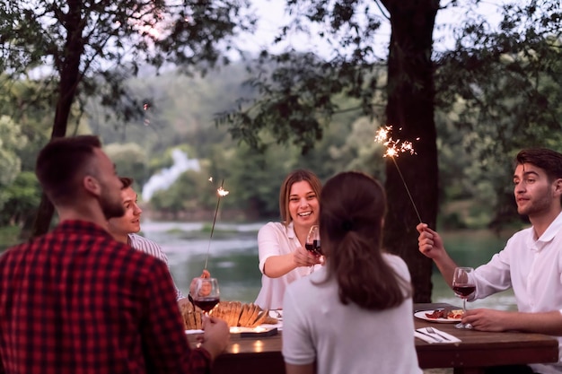 groupe d'amis heureux ayant pique-nique dîner français en plein air pendant les vacances d'été près de la rivière dans la belle nature